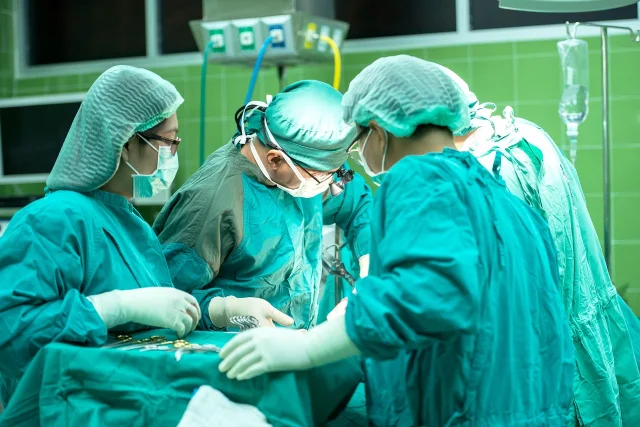 Surgical team in gowns and masks performing an operation under operating theatre lights