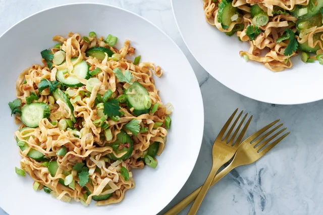 Cold peanut ginger noodles in a wide bowl with sesame seeds and scallions