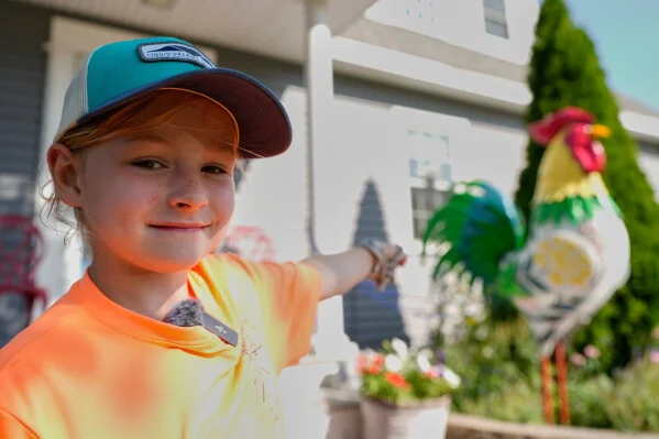 Pyper Leblanc stands beside a colorful tin rooster in Ogunquit, Maine.