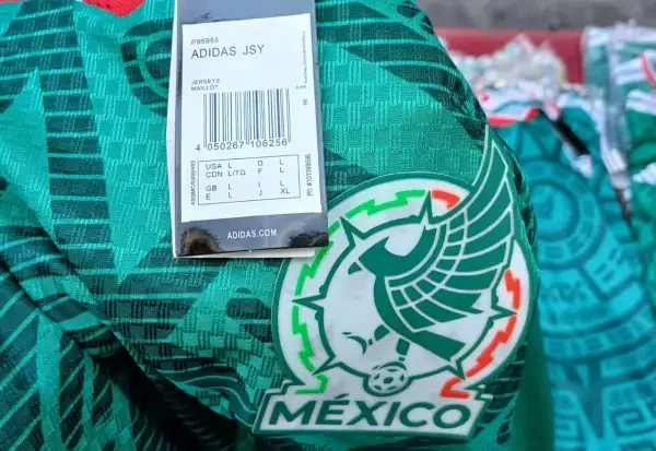 A counterfeit Mexico national team jersey on a hanger among others at a Centro Histórico street stall, Adidas logo visible