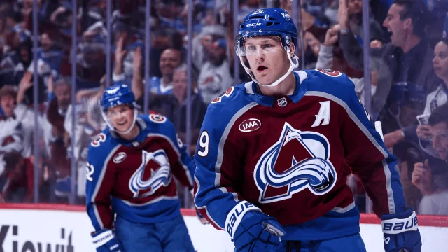 Nathan MacKinnon in a maroon Avalanche jersey on the ice during Colorado's home opener at Ball Arena