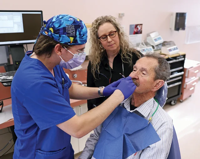 A fourth-year dental student fits dentures on a patient while a faculty clinician supervises in the University of Manitoba dental clinic.
