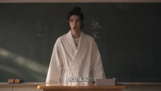 黑板前站着一位系着白色长袍、把头发束成发髻的年轻男子,黑板上写有粉笔字,画面下方是中文字幕。