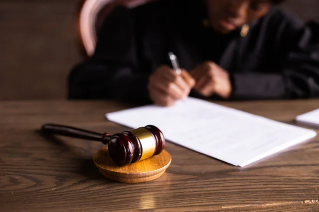 A judge signing court documents beside a gavel, representing the criminal sentencing phase of the Cendant fraud prosecutions