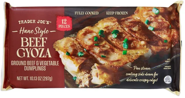 A sealed bag of Trader Joe's Hane Style Beef Gyoza photographed straight on against white: the words "TRADER JOE'S", "Hane Style", "BEEF GYOZA" and "GROUND BEEF & VEGETABLE DUMPLINGS" printed down a maroon panel on the left, a red badge reading "12 PIECES" at the top, a photograph of six golden pan-fried dumplings joined by a lacy crisp sheet across the front, a white arrow pointing at them with the line "Pan steam coating side down for delicate crispy edge!", and "NET WT. 10.13 OZ (287g)" along the bottom left corner