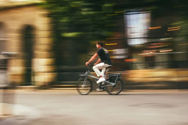 Man riding an electric bike through a city street with motion blur