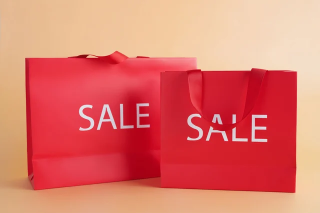 Two red luxury retail bags labeled SALE on a neutral background, representing a time-limited shopping credit
