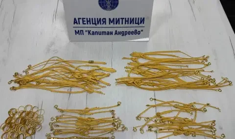 Spread of thin gold necklaces and small rings laid on a table in front of a sign reading "Агенция Митници / МП Капитан Андреево"