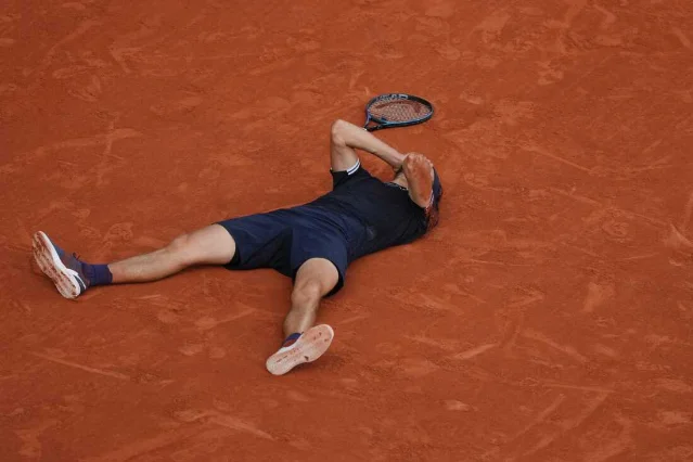 Alexander Zverev lies on the clay of Court Philippe-Chatrier after winning Roland Garros 2026