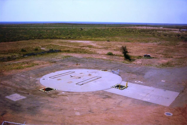 Aerial view of the Atlas F missile silo cap at Site 4, Roswell New Mexico — a concrete circular platform in flat desert scrubland with blast door frames visible