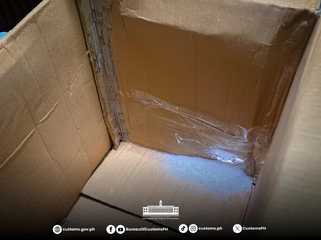 Interior of an opened cardboard parcel with white powder residue in the bottom corner, Philippine Bureau of Customs branding visible — one of the 14 seized parcels