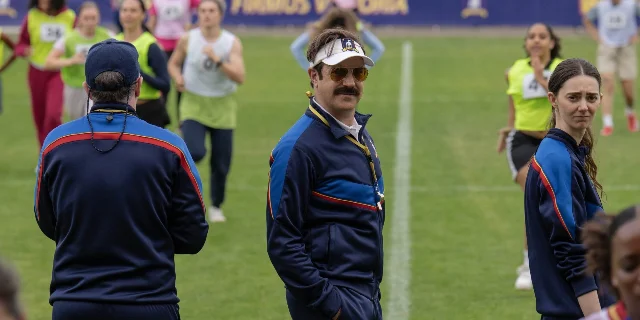 Jason Sudeikis as Ted Lasso on the football pitch with coaching staff in Ted Lasso S4 on Apple TV+