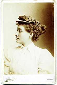 Annie Londonderry in a studio portrait, wearing a hat and light blouse