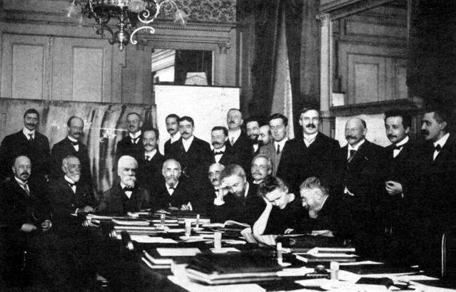 The 1911 Solvay Conference photo — Einstein stands immediately behind and to the right of Langevin; Curie sits at the table, the only woman among 24 physicists