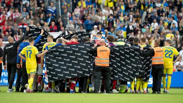 Denmark and Ukraine players, along with security personnel, forming a protective ring around Eriksen on the pitch in Odense