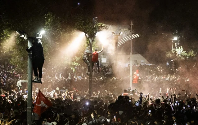 Arsenal supporters flood the streets after the title is confirmed, red smoke and scarves everywhere