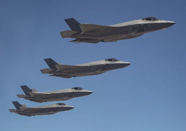 Four F-35A Lightning II jets in close formation against a clear blue sky