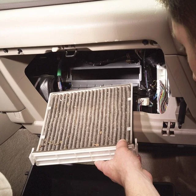 Old cabin air filter sliding out of its tray