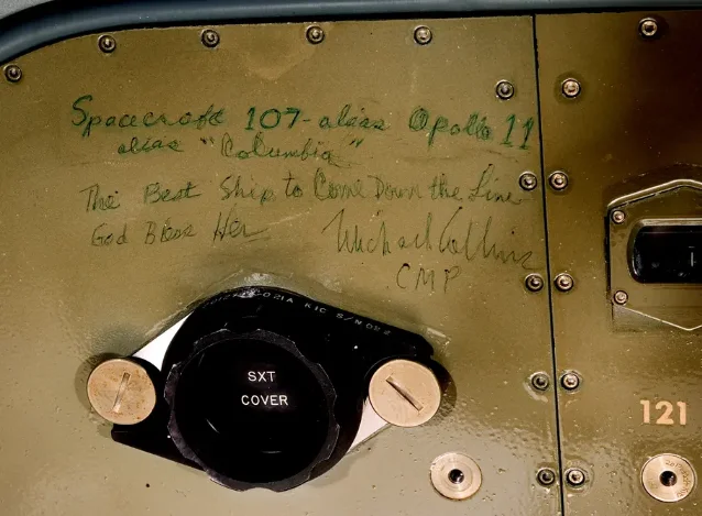 Michael Collins's inscription on the lower equipment bay panel of Columbia, written after splashdown: "Spacecraft 107, alias Apollo 11, alias 'Columbia.' The Best Ship to Come Down the Line. God Bless Her. Michael Collins, CMP." The SXT COVER knob for the sextant housing is visible below.