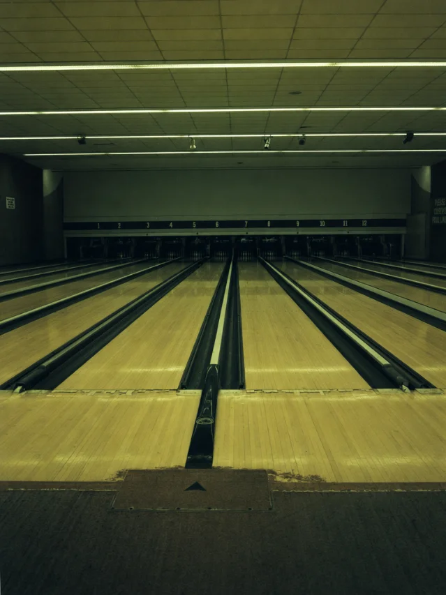 Bowling alley lanes receding to dark pin-setter machinery