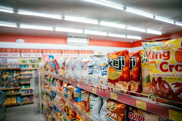 A supermarket snack aisle lined with brightly colored packaged chips and processed foods