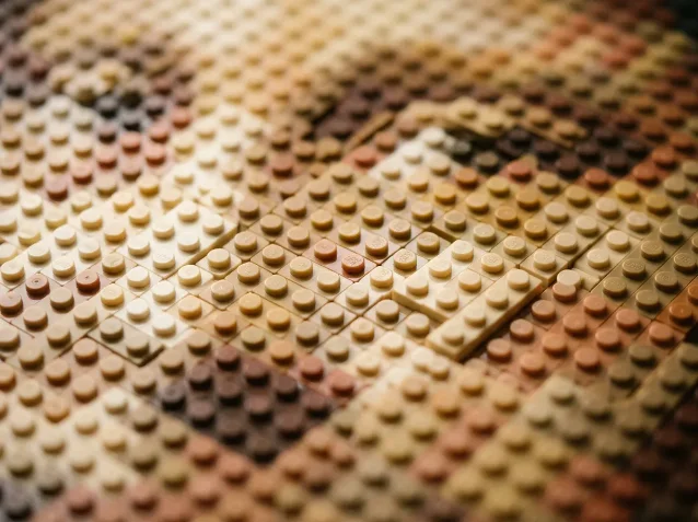 Close-up macro of LEGO flat stud plates in warm ivory, beige, tan and brown tones arranged in a mosaic pattern, shallow depth of field
