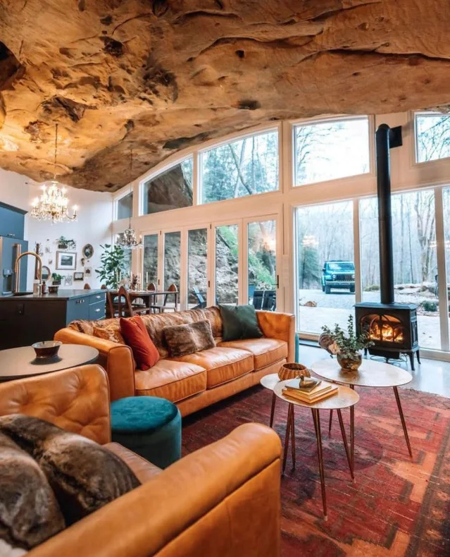 A leather sofa, stove, chandelier, glass front wall, and natural sandstone ceiling inside Dunlap Hollow Cave