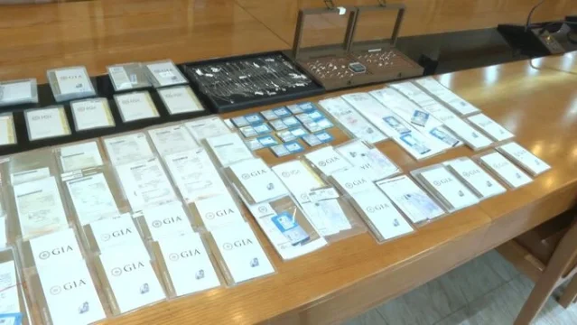 Diamond certificates and jewelry laid out on a wooden table
