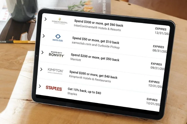 Amex Offers list displayed on a tablet showing merchant logos, offer terms, and expiry dates for hotel and shopping rewards