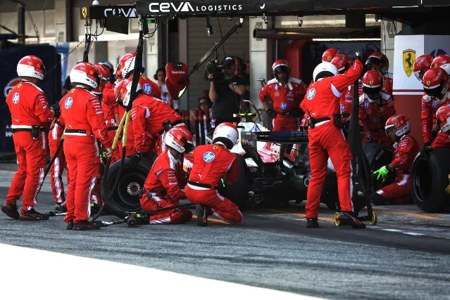 Ferrari pit crew in red suits executing a pit stop during the 2026 Barcelona Grand Prix, HP and Shell sponsor logos visible overhead
