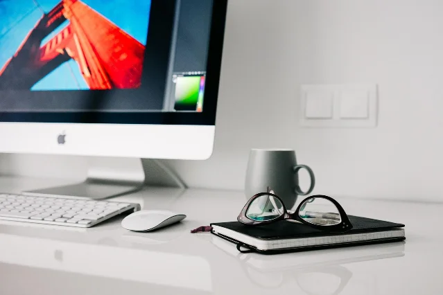 Clean desktop with monitor, notebook, mug, and glasses