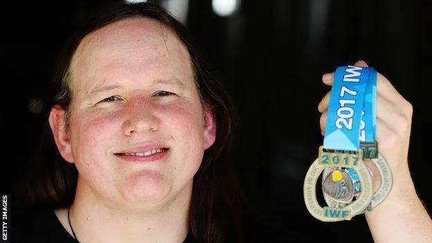 Hubbard holding her 2017 IWF World Championship silver medal up toward the camera, smiling, medal ribbon reading "2017 IWF"