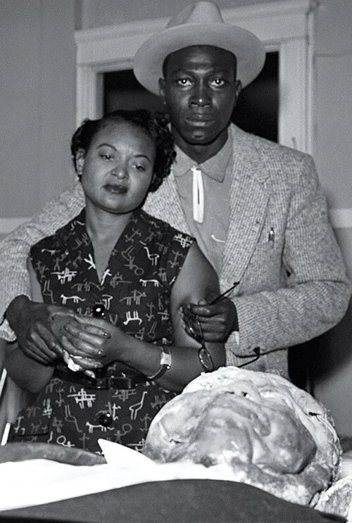 Mamie Till-Mobley and Gene Mobley stand over Emmett Till's open casket, September 1955