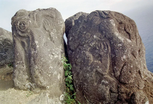 Two birdman petroglyphs carved on basalt rocks at Orongo, Easter Island, showing bird-headed human figures with the Pacific Ocean in the background