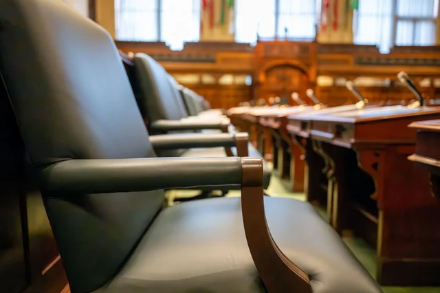 Empty seats and microphones in a government hearing chamber