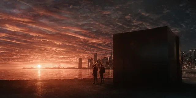 Two figures standing before a glowing alien city skyline and a mysterious monolith at dusk in Dark Matter S2 on Apple TV+