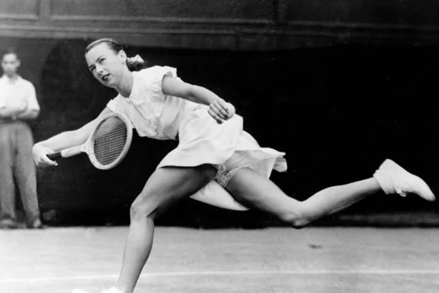 Gussie Moran at full stretch mid-court at Wimbledon 1949, lace-trimmed knickers fully visible, a single male spectator watching in the background