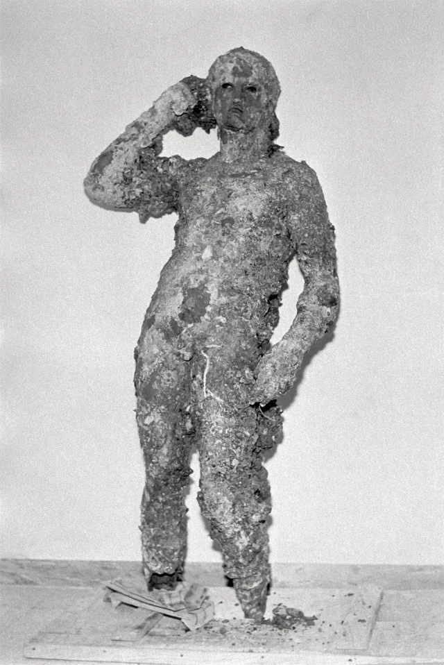 The statue as it appeared before conservation treatment — encased in nearly two thousand years of marine concretion