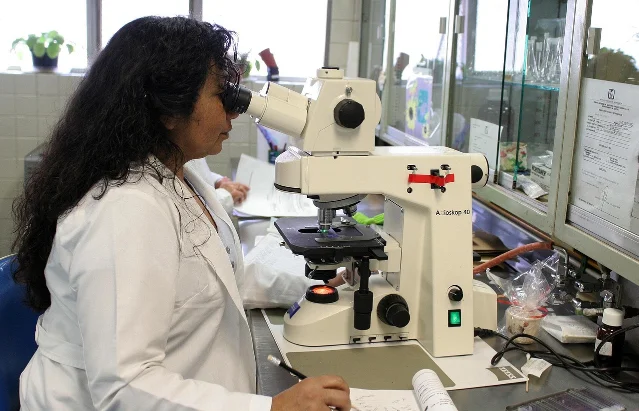 Researcher in a laboratory using a microscope — representing clinical science