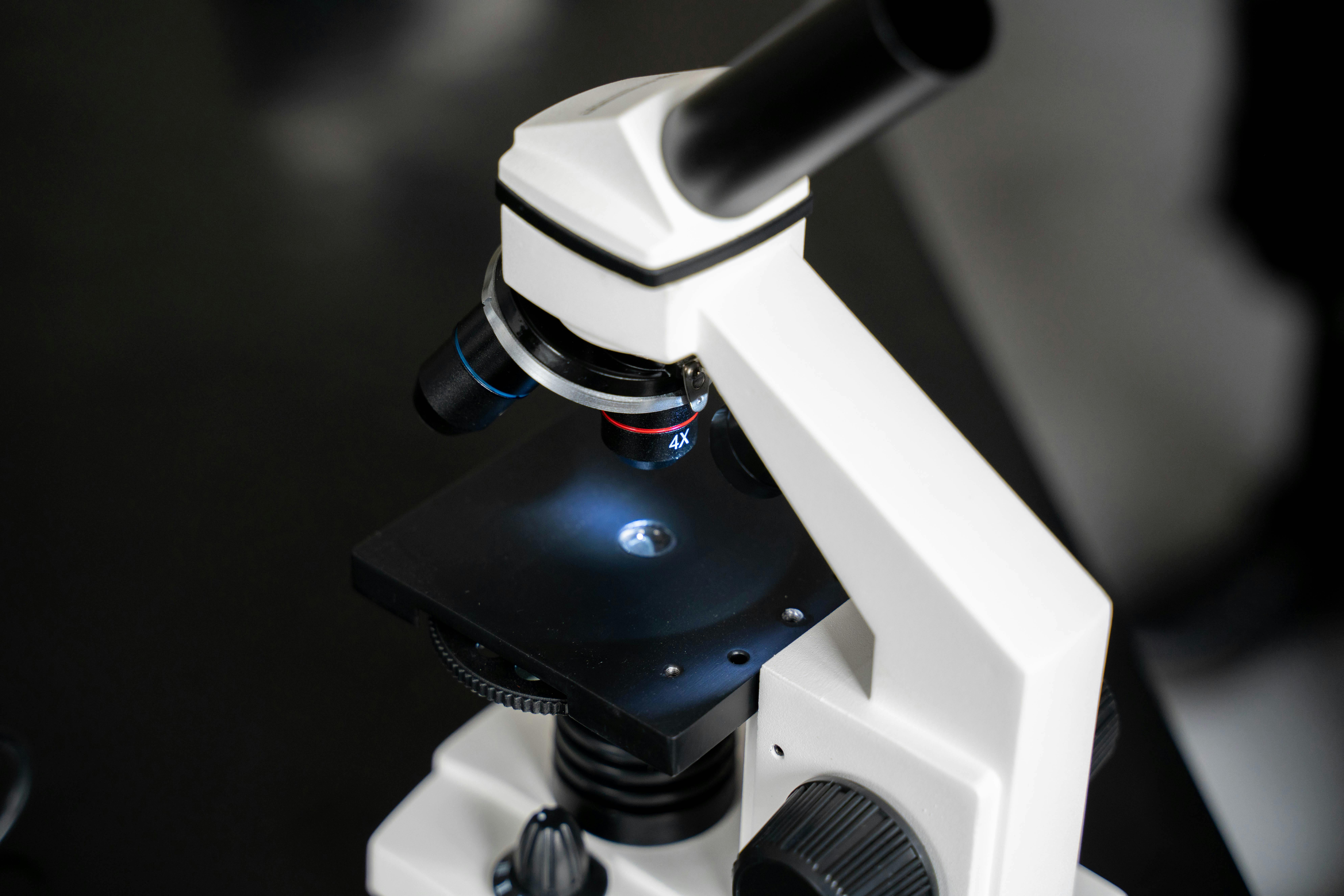 Close-up clinical microscope in dark laboratory — editorial cover image for hantavirus briefing May 13, 2026