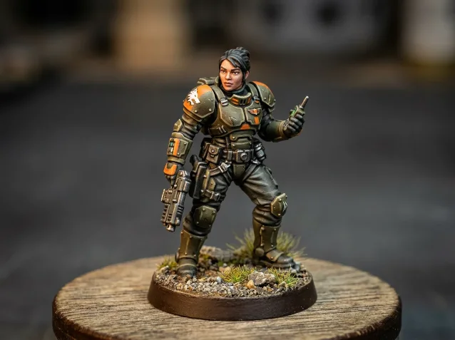 Painted 28mm sci-fi female officer miniature in olive and orange armor on a wooden terrain base