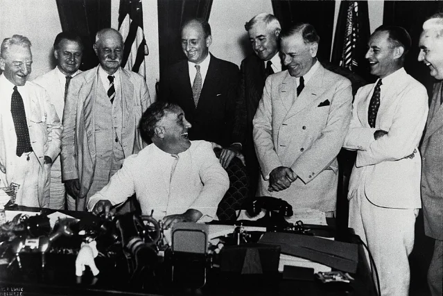 FDR signs the Banking Act of 1933 on June 16, surrounded by lawmakers