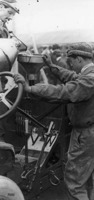 Szisz and his riding mechanic M. Marteau refilling the Renault's radiator during a pit stop on race day