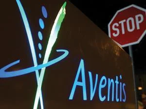 Aventis corporate signage photographed at night alongside a red STOP sign — an image that circulated widely during the hostile bid as a visual shorthand for management's resistance