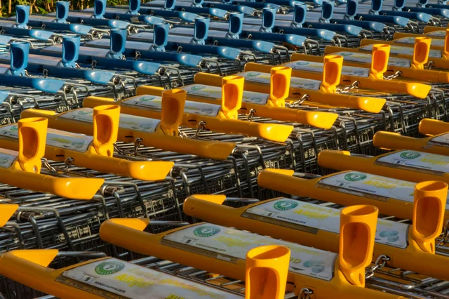 Rows of shopping carts with colorful handles lined up outside a store