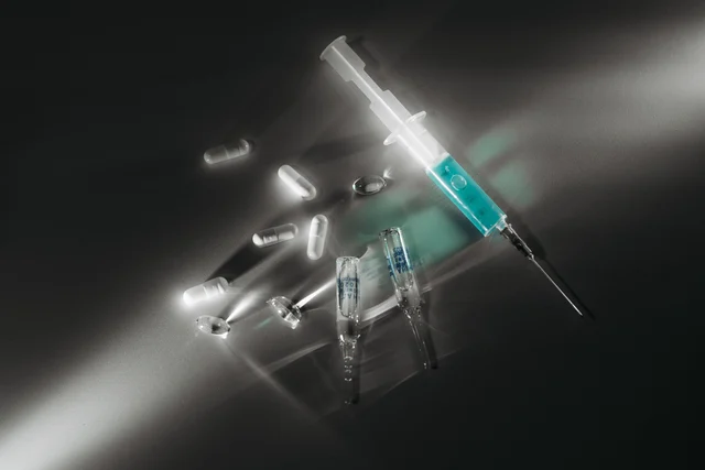 Syringe and capsules under dramatic light (Pavel Danilyuk / Pexels)