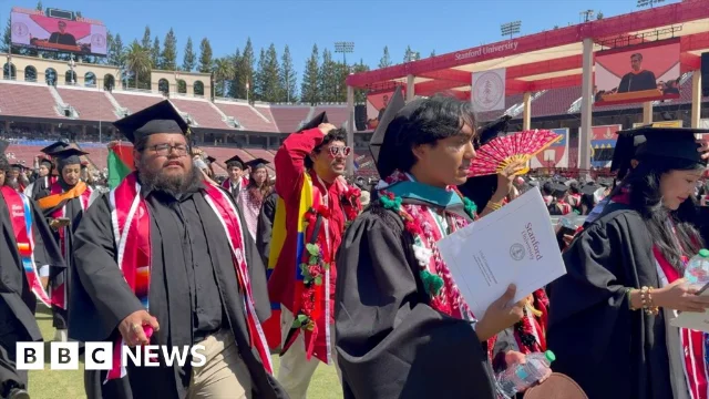 Stanford Stadium during the 135th commencement — students walking out as Pichai takes the stage