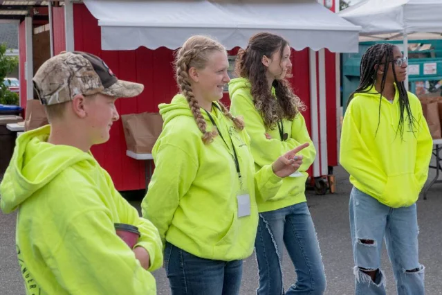 Teen volunteers in bright hoodies stand at the food bank distribution site