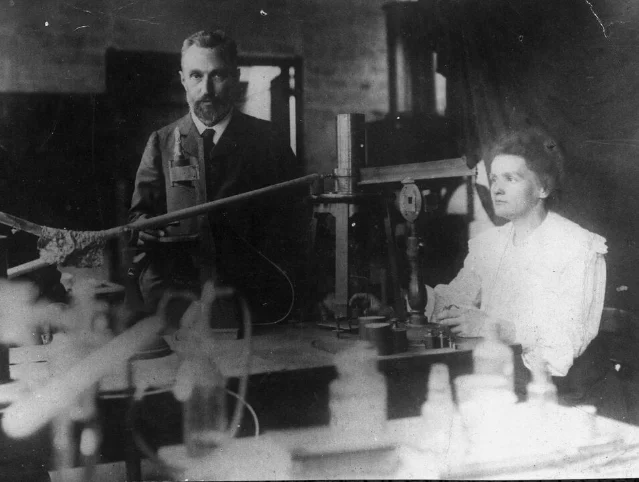 Marie and Pierre Curie working at instruments in their laboratory