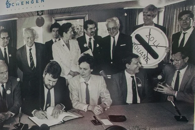 The 1985 Schengen Agreement signing ceremony aboard the MS Princesse Marie-Astrid, showing signatories at a table with a crossed-out border control sign visible in the background